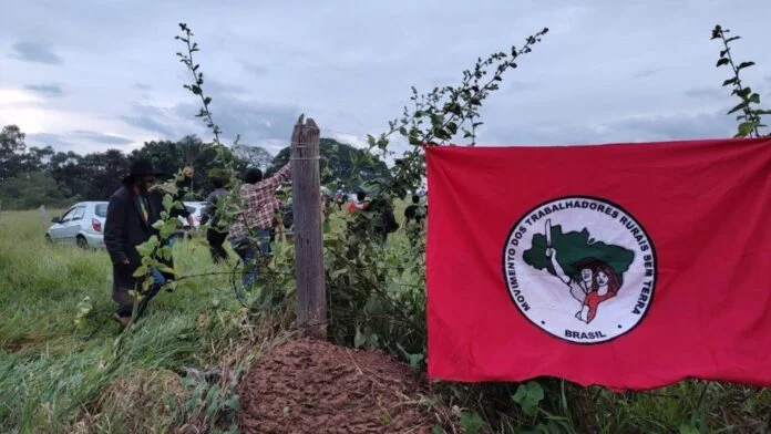 Bandeira do MST em área rural representa debate sobre conflitos por terra no Brasil