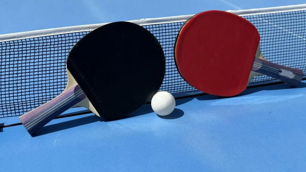 Jogador acompanha trajetória da bola em partida de tênis de mesa