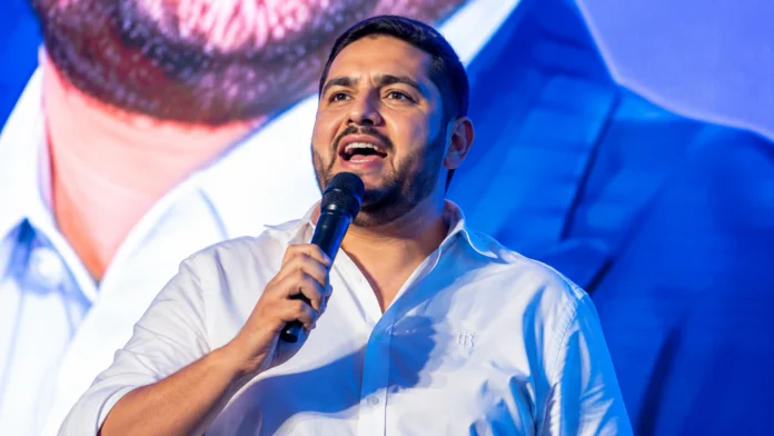 Imagem ilustrativa de homem discursando ao microfone, em reportagem sobre Thiago Ganem e o PL de Minas Gerais.